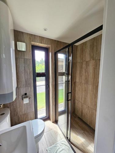a bathroom with a toilet and a glass shower at Hytte Na Wyspie -,,Roztoczańskie Morze'' in Kulików