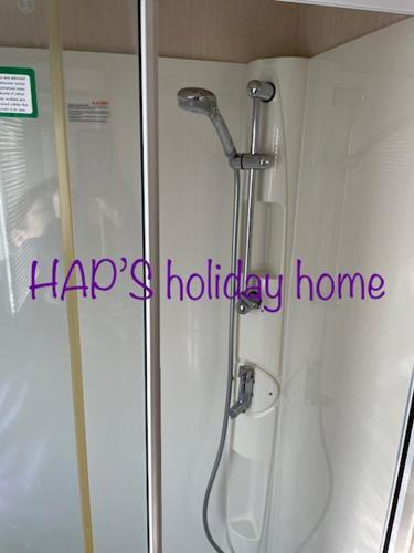 a shower in a bathroom with a happy holiday home sign at HAPs Holiday Home - Haven The Orchards in Brightlingsea