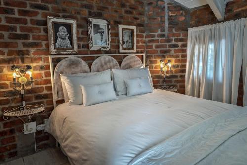 a bedroom with a large bed in a brick wall at Los Olivos at the Yard in Franschhoek
