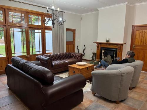 a living room with leather furniture and a person sitting in a fireplace at Grey Ghost Lodge in Cradock