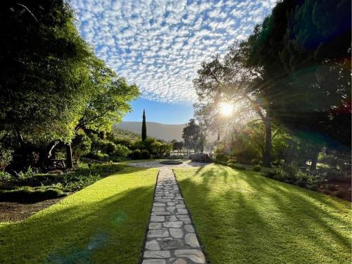 a stone path in a park with the sun shining at Grey Ghost Lodge in Cradock
