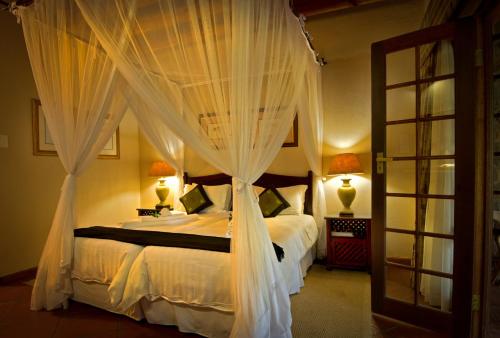 a bedroom with a bed with white drapes at Blyde River Canyon Lodge in Hoedspruit