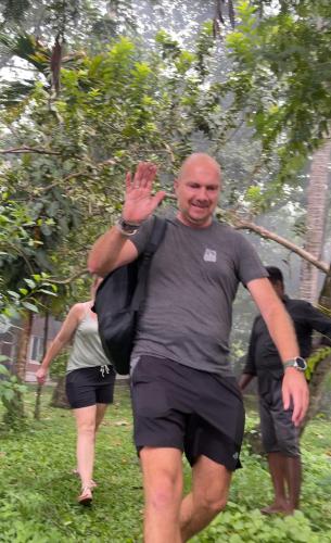 a man walking in the grass with his hand in the air at AshtamudiVillas in Kollam