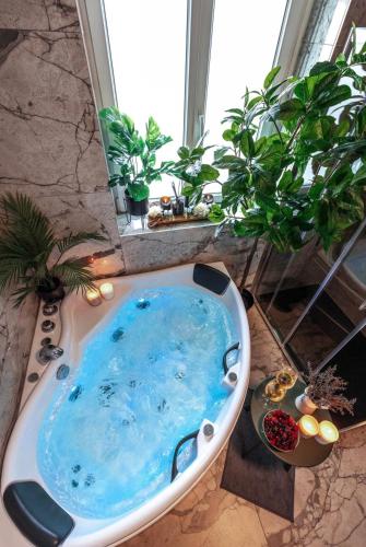 a bath tub with blue water in a bathroom at Prestige Lumineux Jacuzzi Parking privé in Mulhouse