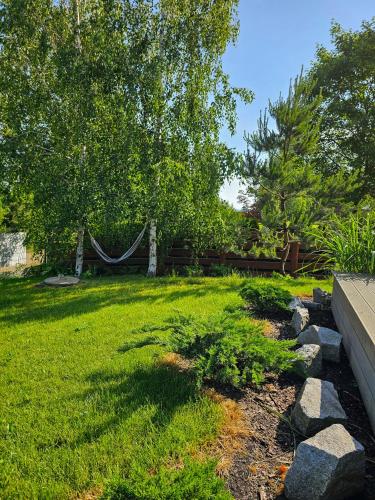 a yard with green grass and a hammock and trees at Hytte Na Wyspie -,,Roztoczańskie Morze'' in Kulików