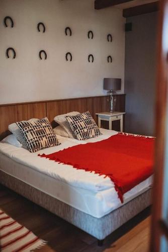 a bed with a red blanket and pillows on it at Gostar in Jelenia Góra