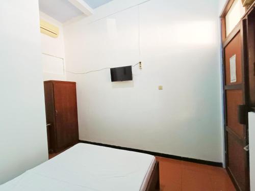 a small room with a bed and a television at YUTAKA INN Stasiun Kota Madiun in Madiun