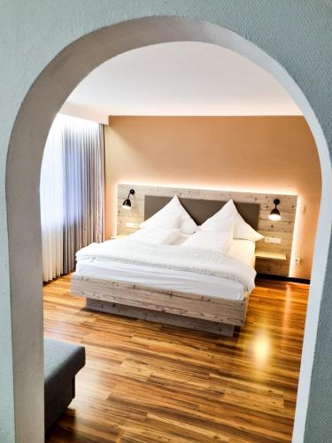 a bedroom with a white bed with an archway at Hotel Landhaus Waldesruh in Freudenstadt