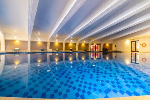 a large swimming pool in a building with blue tiles at Sousse Pearl Marriott Resort & Spa in Sousse