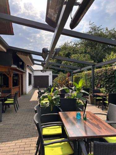 eine Terrasse mit einem Holztisch und Stühlen in der Unterkunft Wiehenkrug in Lübbecke