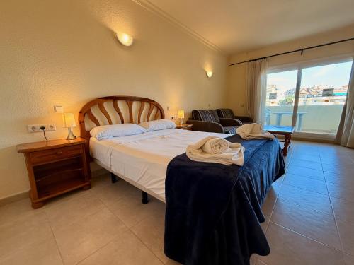a bedroom with a bed and a couch and a window at Kingfisher Apartments Benal Beach in Benalmádena