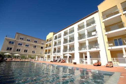 a swimming pool in front of a building at Le T2 Green, 4 pers, clim, piscine, parking in Juvignac