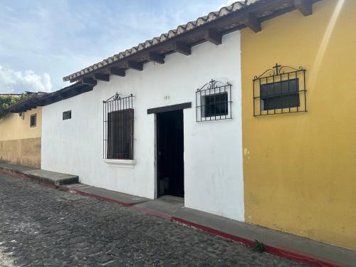 a yellow and white building with a door and windows at Hostal Casa La Merced in Antigua Guatemala