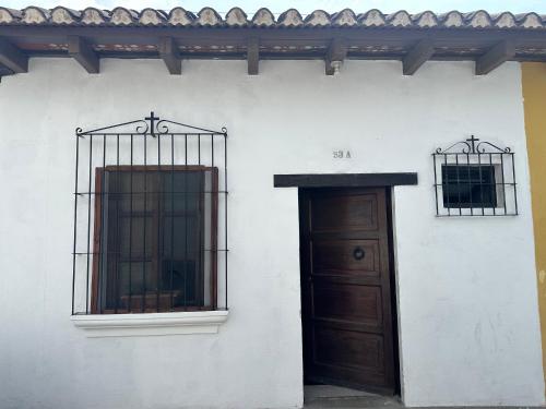 a white building with a door and two windows at Hostal Casa La Merced in Antigua Guatemala