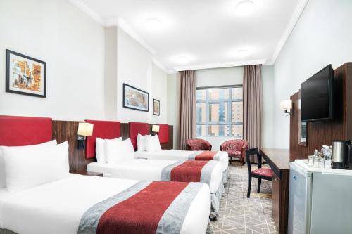 a hotel room with three beds and a flat screen tv at Elaf Bakkah Hotel in Makkah