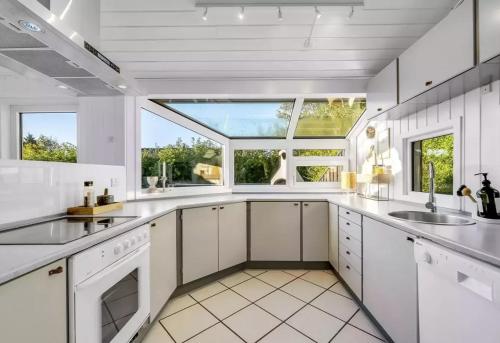 a kitchen with white cabinets and a large window at Fjordferie Hemmet Strand in Hemmet