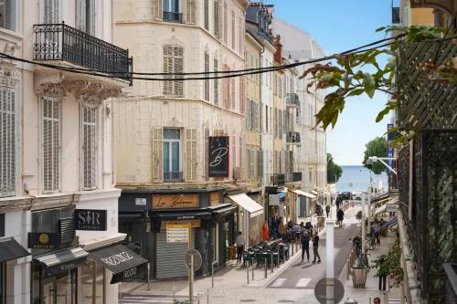 a street with buildings and people walking down a street at Le XV Cannes in Cannes