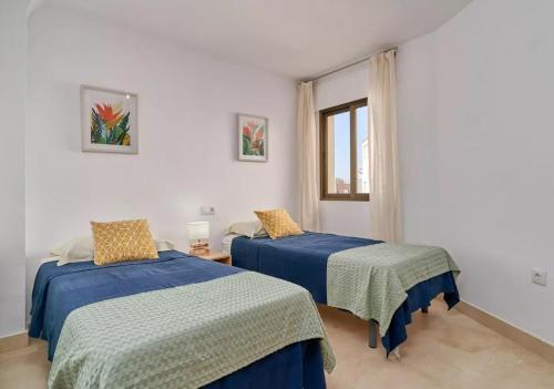 ein Schlafzimmer mit zwei Betten mit blauer Bettwäsche und einem Fenster in der Unterkunft Apartamento Alcazar in Almuñécar