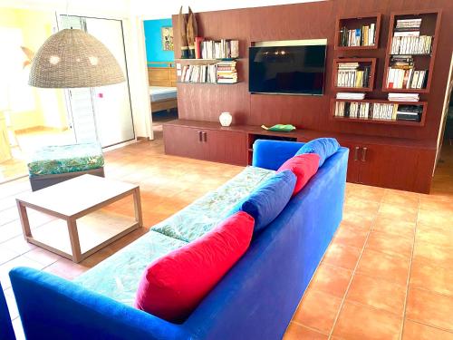 a blue couch with red pillows in a living room at Marisol les pieds dans l eau in Le Gosier