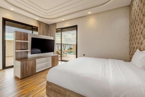 a bedroom with a large bed and a television at Villa de plain-pied avec piscine chauffée à Marrakech in Marrakech