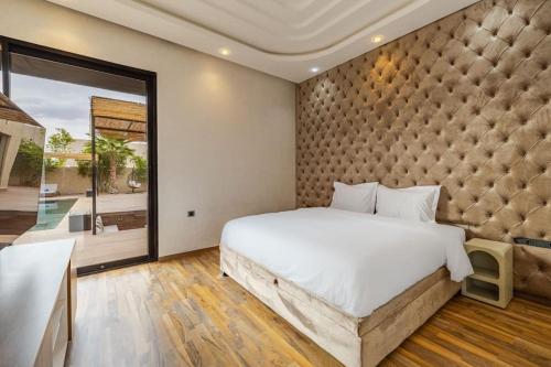 a bedroom with a large bed and a large window at Villa de plain-pied avec piscine chauffée à Marrakech in Marrakech