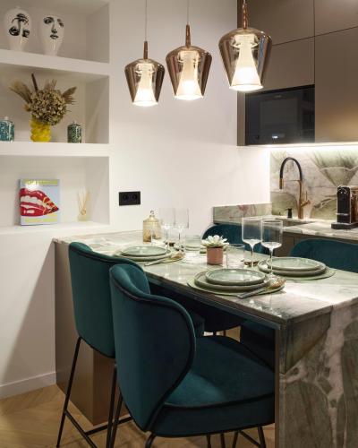 a kitchen with a table with green chairs and lights at Le XV Cannes in Cannes