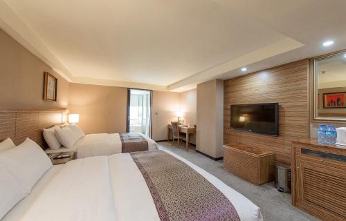 a hotel room with two beds and a flat screen tv at Arsma Hotel in Hualien City
