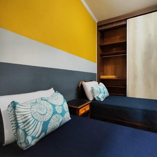a bedroom with a bed and a yellow wall at Casa de Praia Muito Aconchegante in Santos