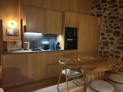 a kitchen with wooden cabinets and a table and chairs at Story Studio Sortelha - Heritage in Sortelha