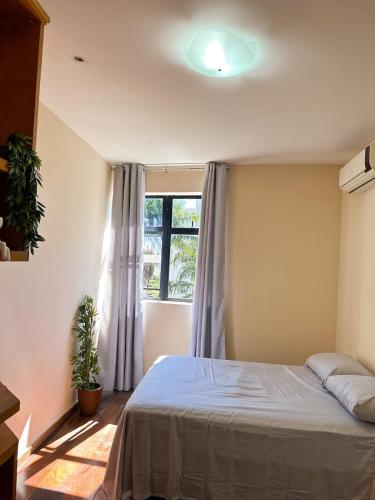 a bedroom with a bed and a window at Apê Letícia I Ar condicionado, wifi e garagem na Zona Sul de BH in Belo Horizonte