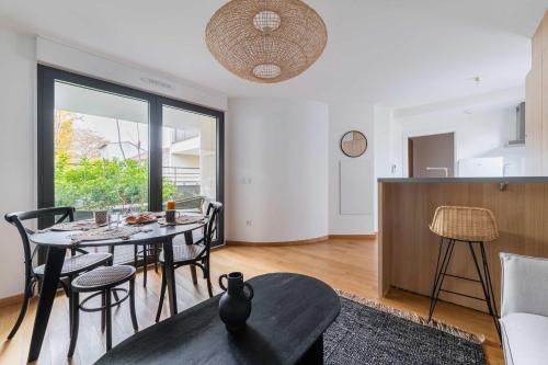 un salon avec une table et une cuisine dans l'établissement Appartement lumineux avec terrasse Courbevoie - 4P - FLAT-GUEST, à Courbevoie