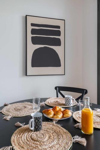 une table noire avec des plaques alimentaires et du jus d'orange dans l'établissement Appartement lumineux avec terrasse Courbevoie - 4P - FLAT-GUEST, à Courbevoie