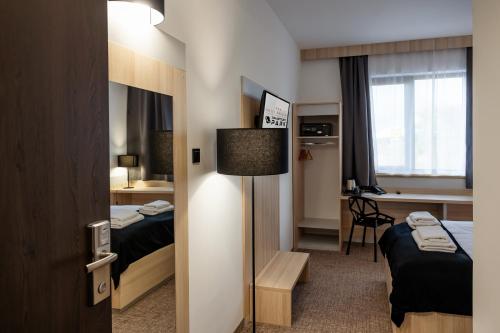 a hotel room with two beds and a desk at Hotel Dworski Galaktyczny Park in Szczecin