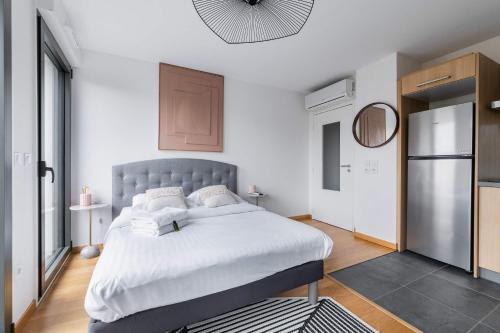 - une chambre avec un grand lit et un réfrigérateur dans l'établissement Studio lumineux avec terrasse Courbevoie - 2P - FLAT-GUEST, à Courbevoie