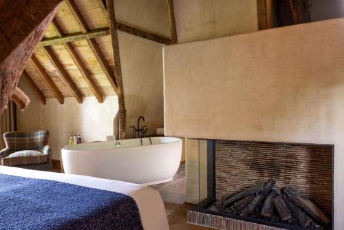 a bedroom with a bath tub next to a fireplace at La Ferme Saint Simeon Spa - Relais & Chateaux in Honfleur
