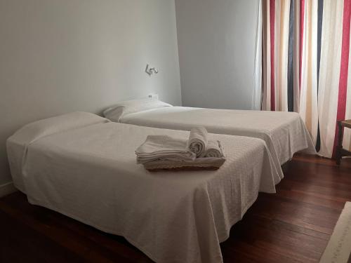 two beds with towels and shoes on top of them at Hotel Boliña in Guernica y Luno