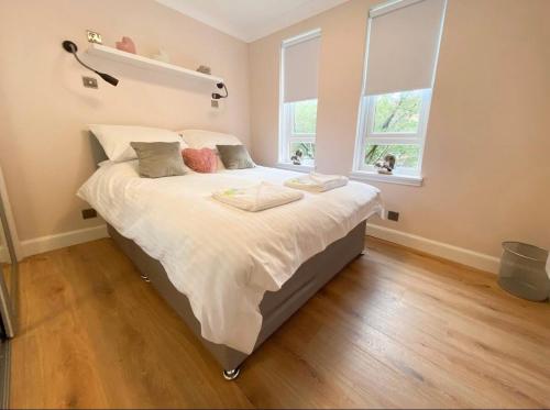 una habitación con una cama grande con sábanas y almohadas blancas en Central two bedroom, Free private parking, en Glasgow