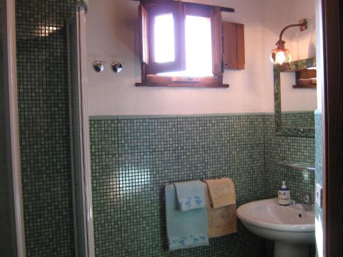 a green tiled bathroom with a sink and a shower at B&B La Torretta in Maratea