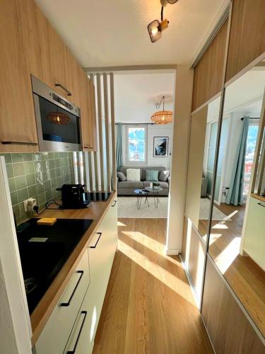 une cuisine avec des armoires blanches et un salon dans l'établissement L'Edelweiss, 2050m La Plagne, F2 Haut de gamme, à La Plagne Tarentaise