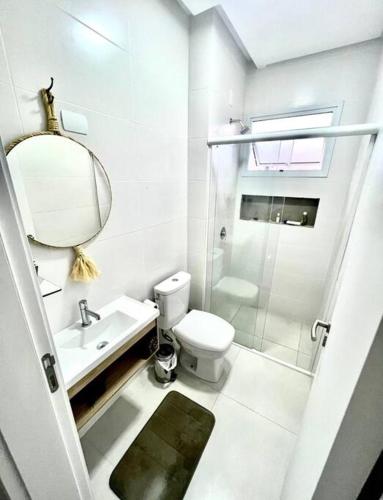 a bathroom with a toilet and a sink and a mirror at Apto em Palmas, 02 quartos, sendo 01 suíte in Governador Celso Ramos