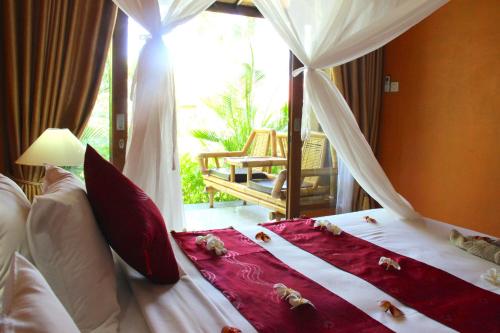 a bedroom with a bed with red and white pillows at Kubuku Eco Dive Lodge and Yoga in Pemuteran