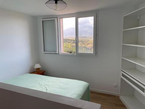 une chambre blanche avec un lit et une fenêtre dans l'établissement Appartement neuf dans hameau proche porto vecchio, à Porto-Vecchio