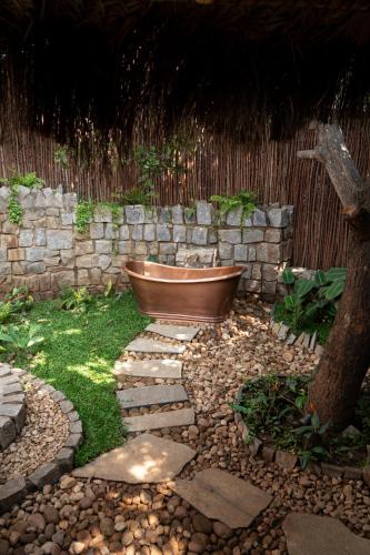 a bath tub sitting in a yard next to a stone wall at The Mudhouse Marayoor in Munnar