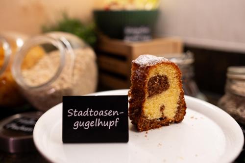 a piece of cake on a plate next to a sign at Stadtoase Kolping Hotel in Linz