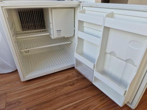 a white refrigerator with its door open on a wooden floor at Private Room Terrace in Kirchheim