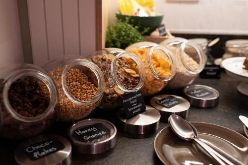 a group of containers of food on a counter with spoons at Stadtoase Kolping Hotel in Linz