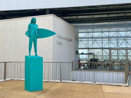 a statue of a woman holding a surfboard on a pedestal at Cozy Carcavelos Beach-NOVA SBE in Carcavelos