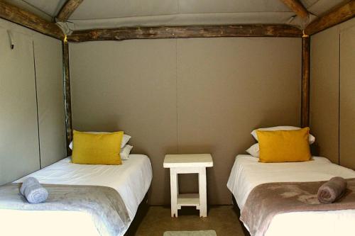 two beds with yellow pillows and a table in a room at Casa Cara Resort in Parys