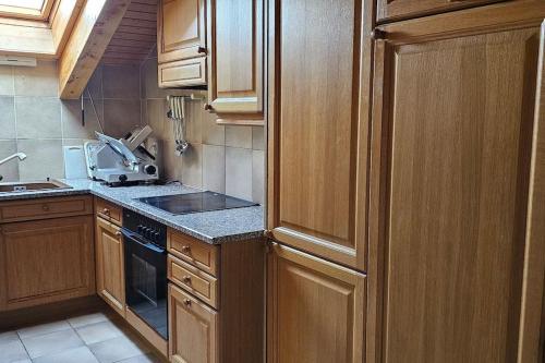a kitchen with wooden cabinets and a stove top oven at Charming Chalet Downtown in Lens