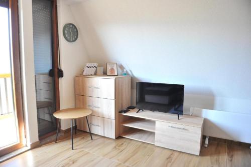 a living room with a television and a desk with a chair at Androv kutak in Andrići